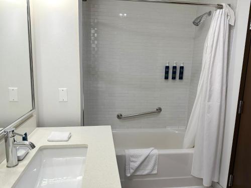 a white bathroom with a tub and a sink and a shower at Four Points by Sheraton Edmonton Gateway in Edmonton