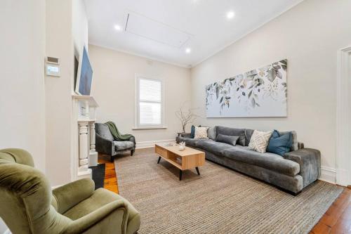 a living room with a couch and two chairs and a table at Waratah Cottage 1910 - Boutique in Glenunga