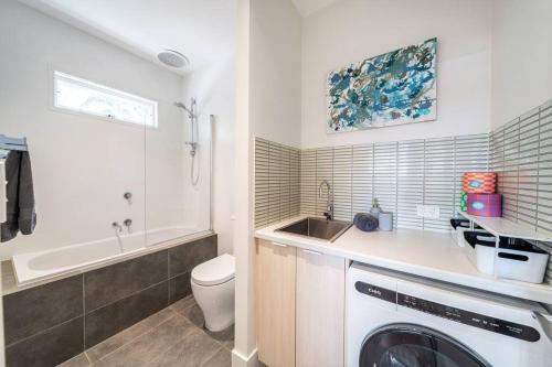 une salle de bain avec un lavabo et une machine à laver dans l'établissement Waratah Cottage 1910 - Boutique, à Glenunga