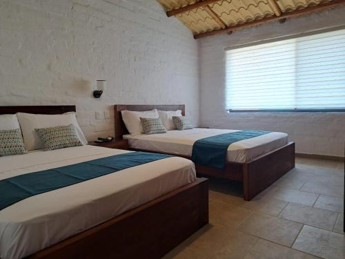 1 Schlafzimmer mit 2 Betten und einem Fenster in der Unterkunft PUNTA COCO VILLAS BEACH in Cojimíes