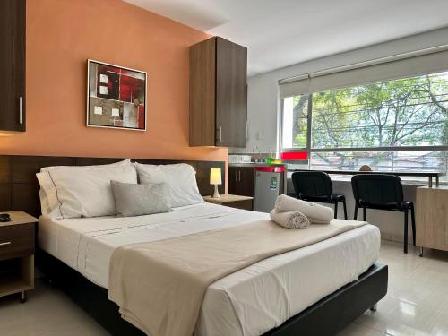 a bedroom with a large bed and a kitchen at Laureles Guest House LGH Hotel in Medellín