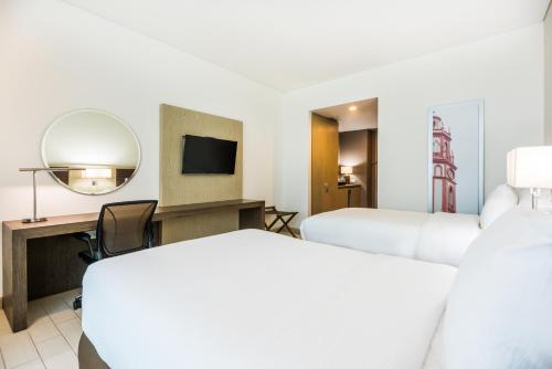 a hotel room with two beds and a mirror at Hilton Garden Inn Barranquilla in Barranquilla