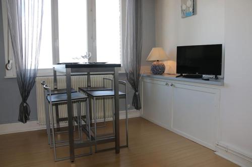 ein Wohnzimmer mit einem TV, einem Tisch und Stühlen in der Unterkunft Escapade vue sur mer in Dunkerque