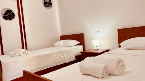 Habitación con 2 camas, sábanas blancas y toallas. en Jessie's apartments, en Durrës