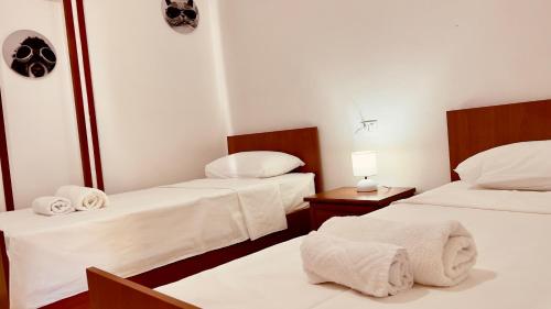 a room with two beds with white sheets and towels at Jessie's apartments in Durrës