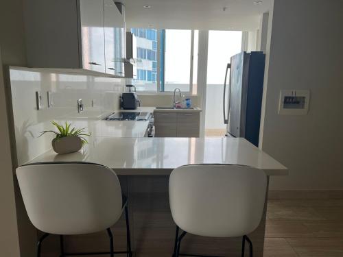 een keuken met een aanrecht met 2 stoelen en een koelkast bij Penhouse vista al mar y ciudad in Panama-Stad