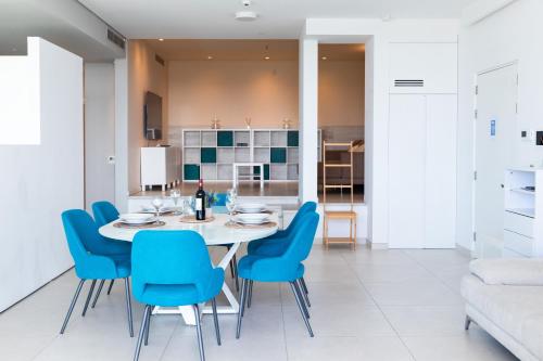 a dining room with a white table and blue chairs at Modern apartment in the center of St Julians in St Julian's