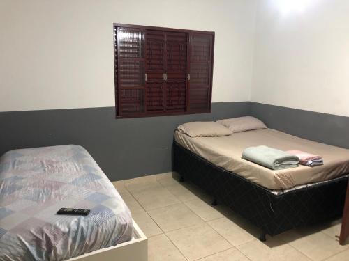 two beds in a room with a window at Suítes Saraiva in Uberlândia