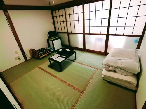a room with a bed and a table and windows at Takachiho B&B Ukigumo in Takachiho