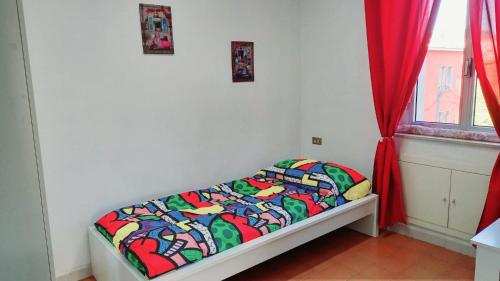 Un dormitorio con una cama con un edredón colorido y una ventana en LG HOUSE casa vacanze, en Nápoles