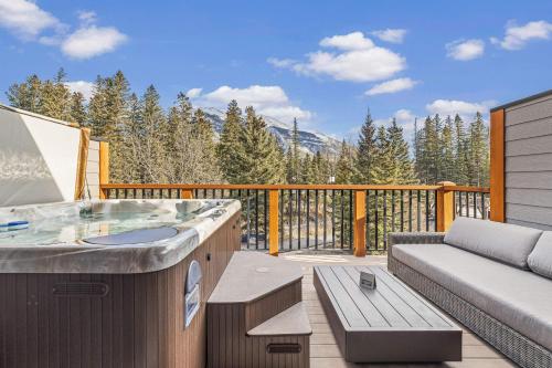 un bain à remous sur une terrasse avec un canapé dans l'établissement Spring Creek Vacations, à Canmore