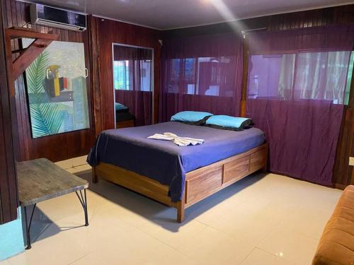 a bedroom with a bed with blue sheets and purple walls at Family-sized Beach Suite in Playa Matapalo in Savegre
