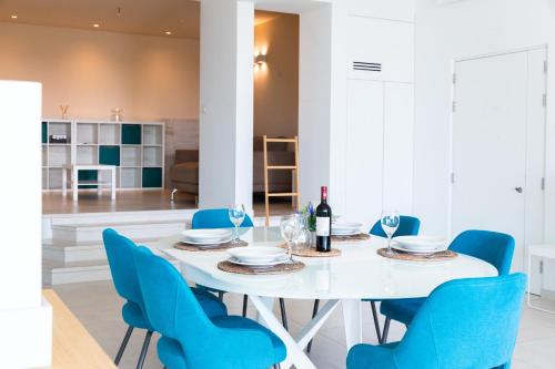 a white dining room with a white table and blue chairs at Modern apartment in the center of St Julians in St Julian's
