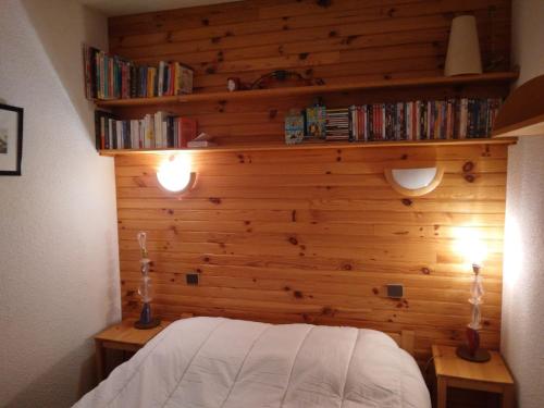 - une chambre dotée d'un mur en bois avec un lit et des livres dans l'établissement Appartement avec parking, près des pistes - FR-1-181-2728, à La Plagne Tarentaise