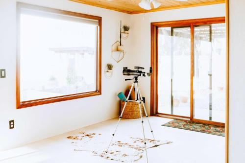 a camera on a tripod in a room with a window at Chic Joshua Tree Pad with Mountain Views and Hot Tub in Twentynine Palms