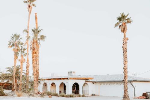 a group of palm trees in front of a building at Chic Joshua Tree Pad with Mountain Views and Hot Tub in Twentynine Palms