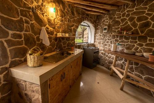 a kitchen with a sink and a stone wall at Bungalow RURU WASI in Urubamba
