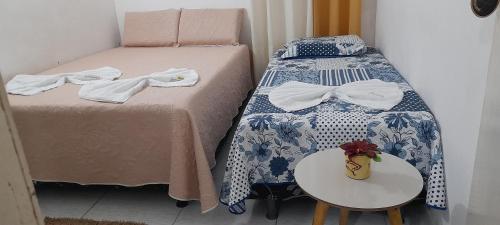 Hospedaria Temporarte في ببرانا: زوج من الأسرة بجوار طاولة مع sidx طاولة صغيرة