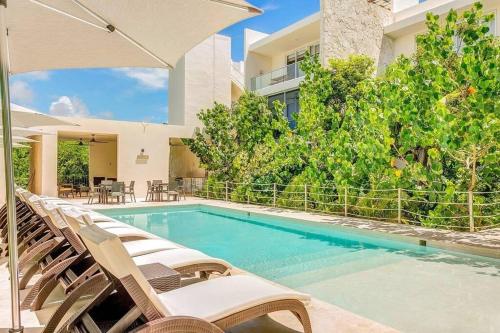 a swimming pool with lounge chairs and an umbrella at Tortuga Azul Private Terrace Rooftop Pool W BBQ Beach Access 11 Pools Free Beach Club in Akumal