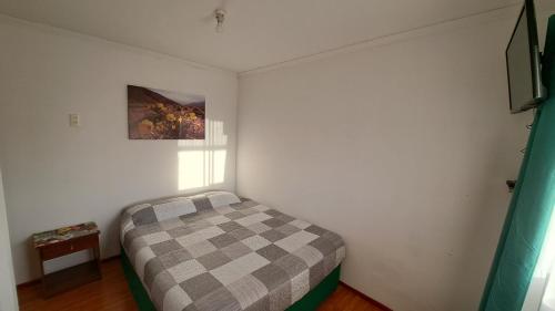 a small bedroom with a checkered bed in it at Hostal Jardín del Desierto in Caldera