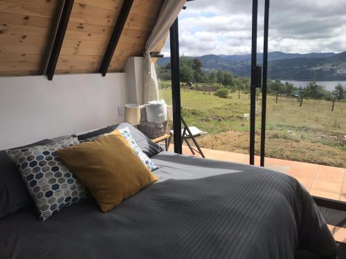 a bedroom with a bed with a view of a field at Refugio El Cacique in Guatavita