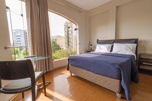 a bedroom with a bed and a table and a window at San Miguel Awanka Hotel in Lima