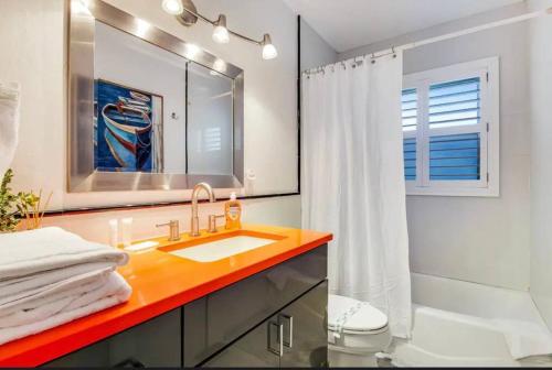 a bathroom with a sink and a toilet and a mirror at Tropical Shores Retreat-10 Min to Siesta Key Beach in Sarasota