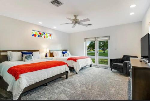 a bedroom with two beds and a flat screen tv at Tropical Shores Retreat-10 Min to Siesta Key Beach in Sarasota