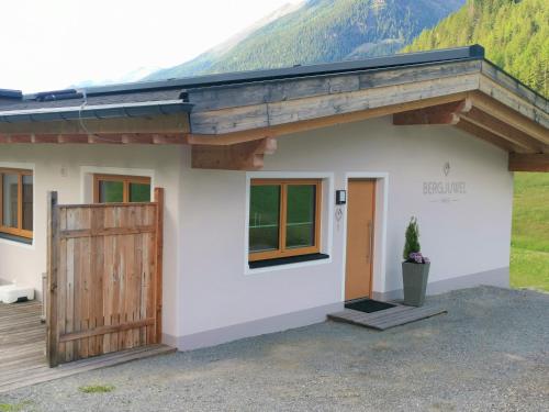 ein kleines weißes Haus mit einer Holztür in der Unterkunft Haus Bergjuwel in Huben
