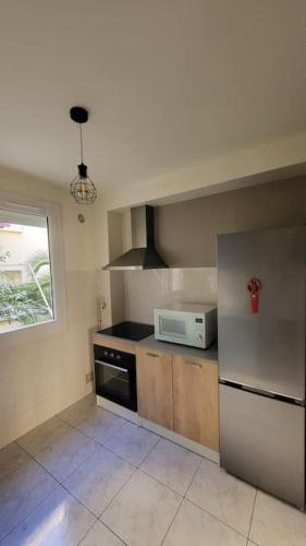 une cuisine avec un réfrigérateur et un micro-ondes dans l'établissement Appartement chaleureux, proche de la gare, à Perpignan