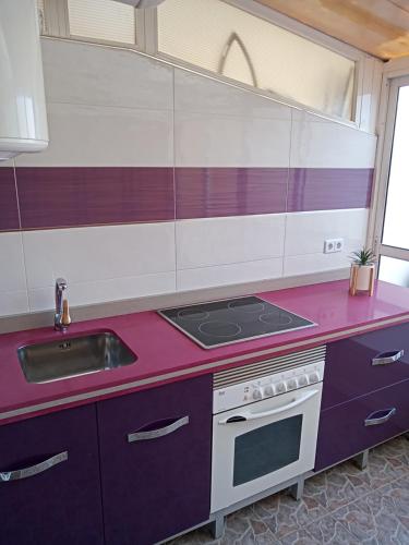 uma cozinha com armários roxos e um forno com placa de fogão em El paraíso del sol em Cartagena