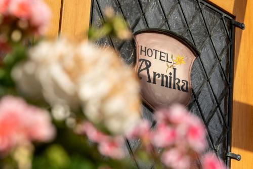 a mirror with a hotel parking sign and pink flowers at ARNIKA Garni in Oberammergau