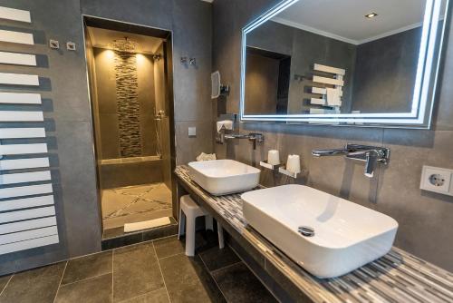 a bathroom with a sink and a mirror and a shower at ARNIKA Garni in Oberammergau