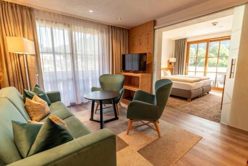 a living room with a couch and chairs and a television at ARNIKA Garni in Oberammergau