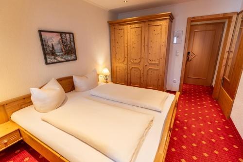 a bedroom with a bed with white sheets at ARNIKA Garni in Oberammergau