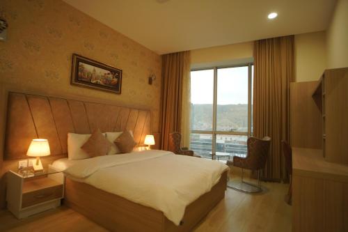 a hotel room with a bed and a large window at Sargali Duhok Hotel in Duhok