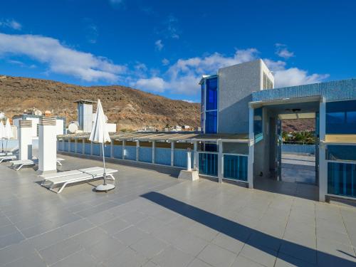 a building with a patio with chairs on the roof at Sunny Valley Apartment in Mogán