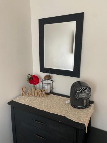 a black dresser with a mirror on a wall at Peaceful Seasonal Wooded Cottage close to everything in Tafton