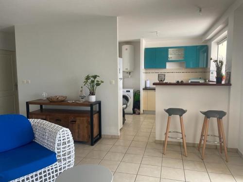 a living room with a couch and a kitchen with blue cabinets at Les terrasses de la Marina in Le Marin