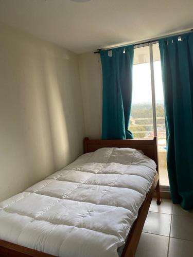una camera da letto con un letto e una finestra con tende blu di Departamento Costa Algarrobo Norte a Yeco