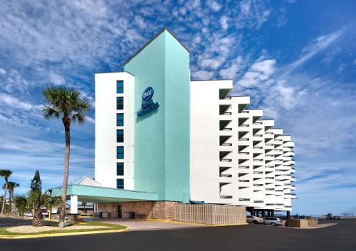 a blue and white building with a palm tree at Best Western New Smyrna Beach Hotel & Suites in New Smyrna Beach