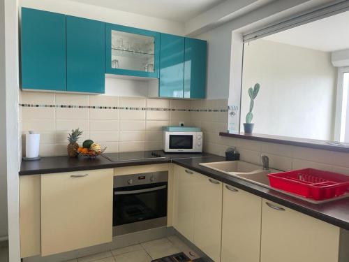 a kitchen with blue cabinets and a sink at Les terrasses de la Marina in Le Marin