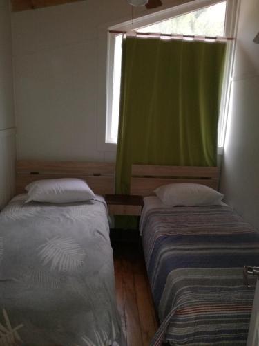 two beds in a room with a green window at Amacoa in Puerto Varas