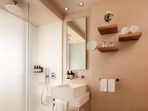 La salle de bains est pourvue d'un lavabo et d'un miroir. dans l'établissement Avani Palazzo Moscova Milan Hotel -Previously NH Palazzo Moscova-, à Milan