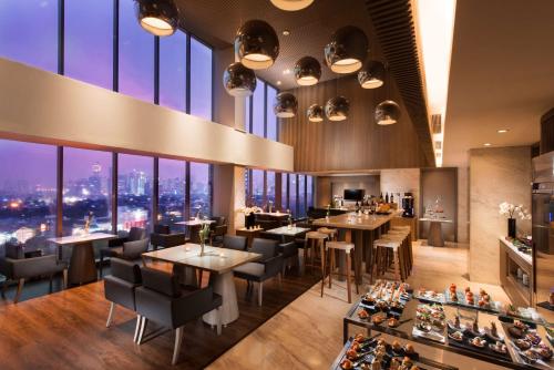 a restaurant with tables and chairs and large windows at DoubleTree by Hilton Jakarta - Diponegoro in Jakarta