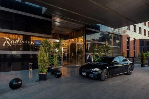 カイロにあるラディソン ブルー ホテル カイロ ヘリオポリスの建物前に停車する黒車