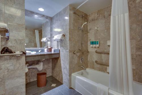 een badkamer met een bad en een douche met een douchegordijn bij Drury Inn & Suites Overland Park in Overland Park