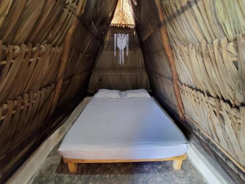 Cama con colchón en una yurta con ventana en Hakuna Matata Glamping, en Bacalar