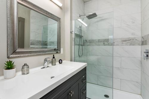 ein Bad mit einem Waschbecken und einer Dusche mit einem Spiegel in der Unterkunft Chic Comforts in Tobin. in San Antonio