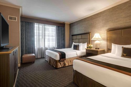 a hotel room with two beds and a flat screen tv at The Whitehall Hotel - BW Premier Collection in Chicago